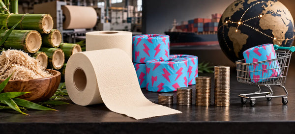 Cream bamboo toilet paper rolls and cyan-pink wrappers beside rising coin stacks, bamboo stalks and a miniature shopping cart, with a cargo ship in the background.